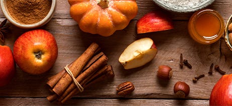 Fall baking ingredients and small pumpkins on a brown cutting board