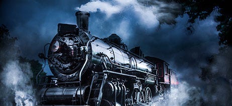 Black steam train riding down the tracks at night