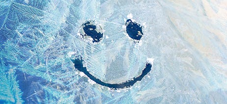 smiley face drawn on ice coating a window