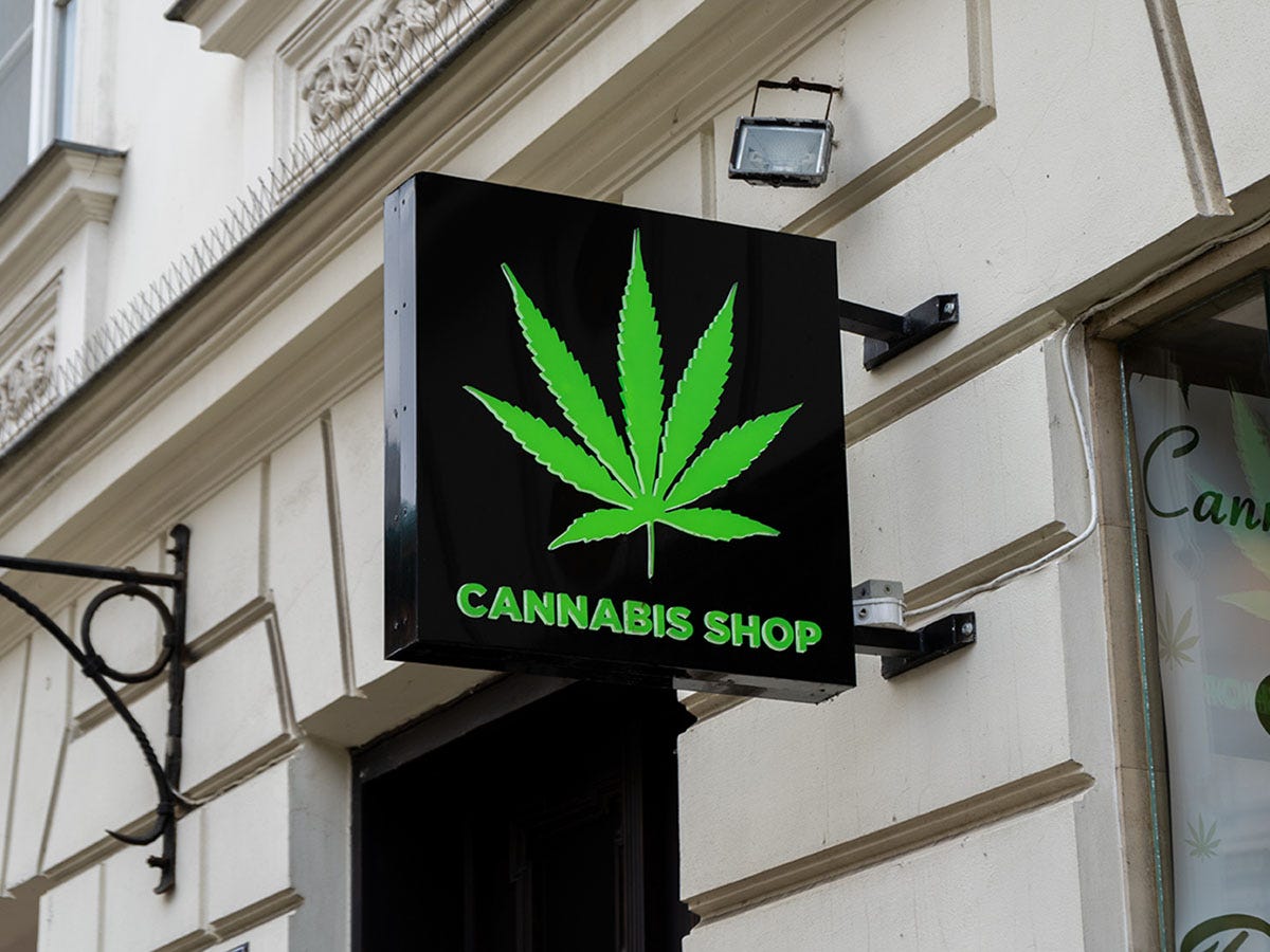 Sign in front of a dispensary that reads 'Cannabis Shop' below a marijuana leaf