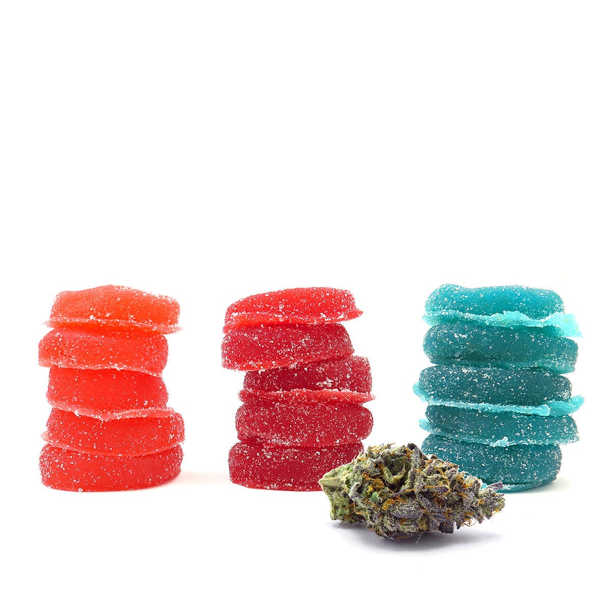 three piles of cannabis gummies behind a nugget of cannabis flower